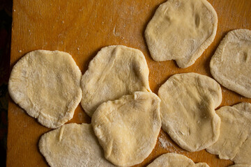 Fresh, Raw Dough Circles Flattened and Dusted with Flour on Wooden Board