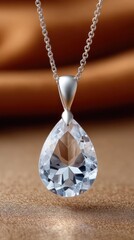 Close Up Of A Pear Shaped Crystal Pendant Necklace With Silver Chain Resting On A Textured Bronze Fabric Background With Soft Lighting