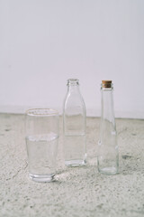 Three Transparent Glass Bottles and Water on Light Floor