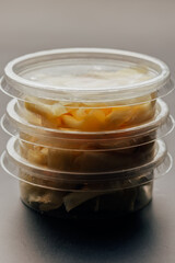 Containers with sauces and ginger on a dark background isolated