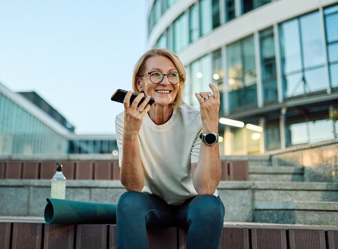 Portrait of a middle aged mature  beautiful sport woman smiling happy and talking at smartphone mobile phone.
