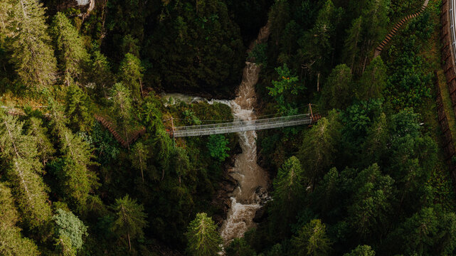 Aerial of the Metal suspension bridge in the Alps near Namlos, Tyrol &ndash; hiking trail through dense mountain forest across a deep gorge