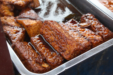 a traditional Indonesian dish consisting of tempeh and tofu seasoned with soy sauce served in a stainless steel container