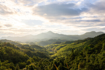A Serene Morning in the Verdant Mountains with Sunlight Filtering Through the Clouds