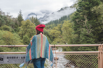 happy woman tourist trekking at mountain in Changping valley near Siguniang mountain in Sichuan province, China, color effect, low key and soft focus.