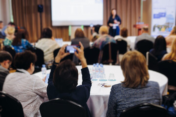 Female audience at the symposyum meeting, participants attendees in conference room hall listens to lecturer, group of women on a medical congress together listen to speaker on a stage at master-class