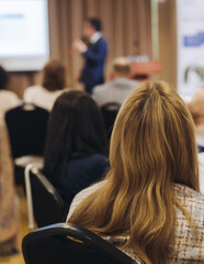 Female audience at the symposyum meeting, participants attendees in conference room hall listens to lecturer, group of women on a medical congress together listen to speaker on a stage at master-class