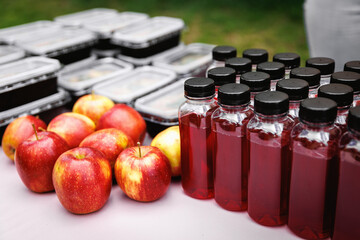 Bottles of red juice and apples on catering table