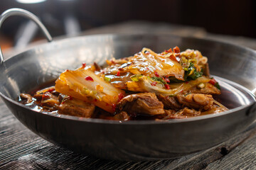 Sichuan lamb ribs with Chinese cabbage. Meat in an iron bowl on a wooden background. Chinese cuisine. Food concepts.