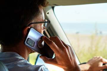 risks behind the wheel. man talking on his cell phone while driving