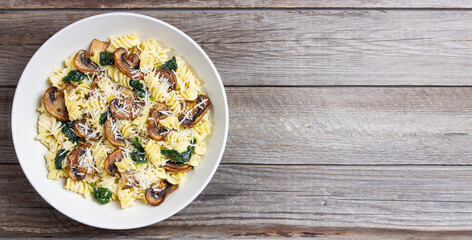 Pasta in a creamy sauce with mushrooms, spinach, and cheese. Italian cuisine. Vegetarian food.