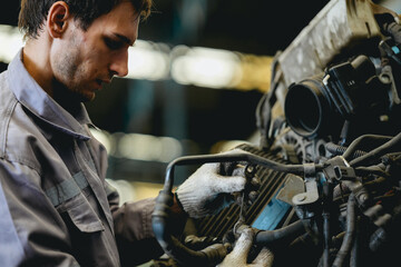 White man technician checking used car damaged engine block at scrap yard warehouse recycle area part. Maintenance engineer inspecting rust oily auto motor old spare part in junkyard for reuse service