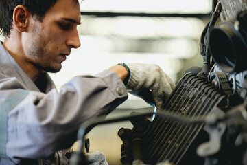 White man technician checking used car damaged engine block at scrap yard warehouse recycle area...