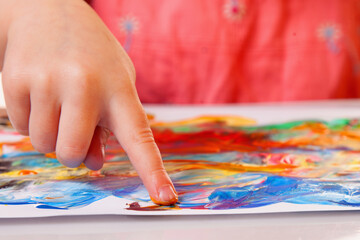 Obraz premium Child finger painting with colorful paint on white paper. Kids creativity, fun learning and art concept.