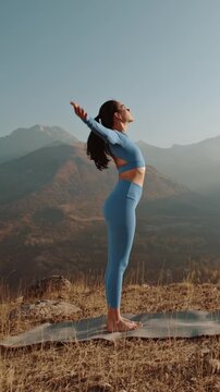 Woman performing sunrise yoga in mountains, slow motion vertical video showing grace, focus and harmony of body and nature