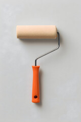 Obraz premium Roller brush rests on a light gray surface, ready for painting projects in a home or office setting