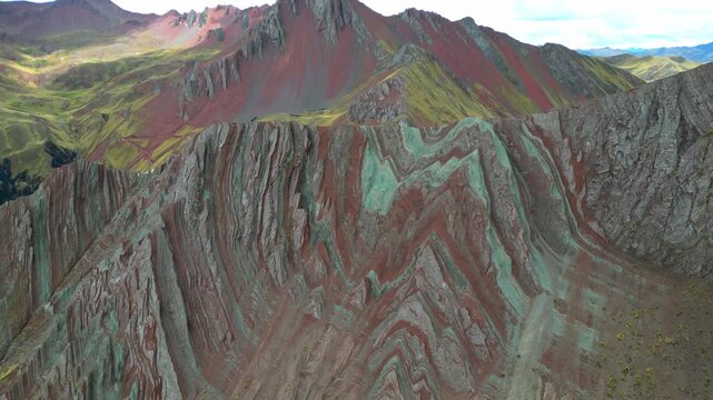 Cinematic 4K flyover of the Palccoyo Rainbow Mountains &mdash; bold red and ochre stripes tracing along steep, jagged slopes at high altitude.