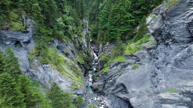 Drone shot revealing a river running through the mountain forming a beautiful canyon and waterfall revealing