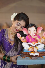 Indian Woman in Traditional Saree Holding Lord Ganesha Idol During Ganesh Chaturthi Celebration