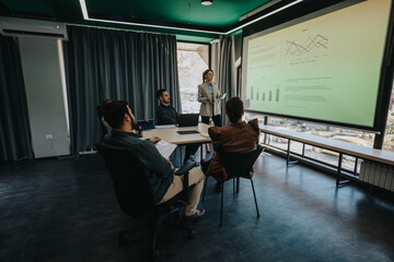 Colleagues collaborating during a meeting, analyzing graphs and charts on a presentation screen.