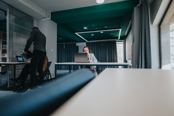 A vibrant workspace featuring people working on laptops in a modern office setting. The scene...