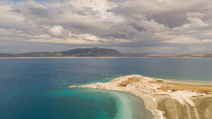 The turquoise waters of Lake Salda and its white stromatolite formations. A unique geological landscape beneath a dramatic cloudy sky.