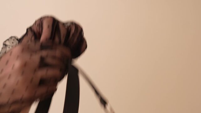 Woman in black transparent gloves holds black leather clamp with plastic ball. BDSM erotic set. Adult toys.