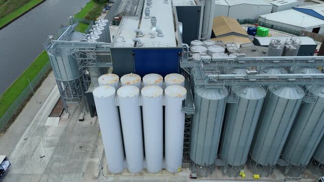 Aerial view of industrial silos reflecting sunlight, contrasting with the dark canal water and assorted buildings near the port, Goole, England, United Kingdom.