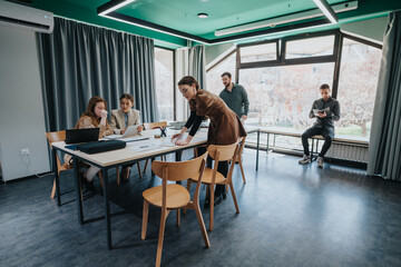 A group of coworkers working together at a bright, modern office space with large windows,...
