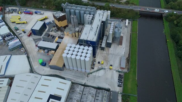 Aerial view of a sprawling industrial complex with cylindrical tanks, a canal, and a bridge, featuring a mix of textures and tones, Goole, England, United Kingdom.