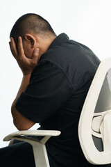 Stressed man sitting in office chair with head in hands facing burnout and anxiety from work