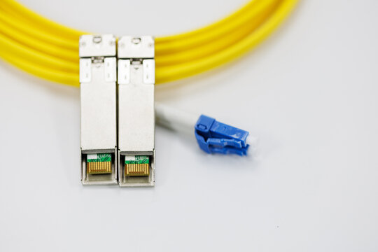 Enabling high-speed data transmission, this coiled fiber patch cord and its blue connectors work in tandem with SFP modules within modern optic networks.