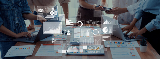 Team members collaborate in a modern office environment analyzing business data, utilizing digital screens, graphs, and reports to drive insights and strategy. Trope