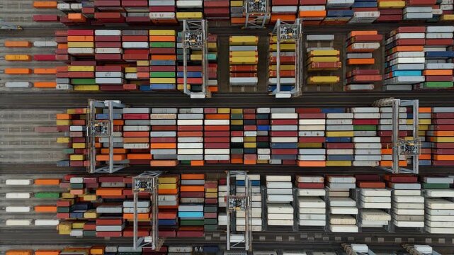 London, United Kingdom - 11 October 2025: Aerial view of neatly stacked shipping containers displaying a vibrant array of colors and patterns in the industrial port.