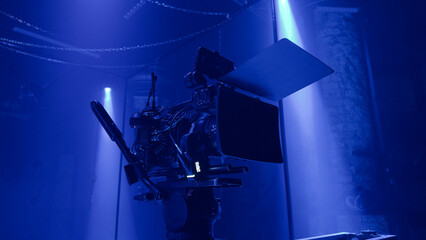 Professional film camera setup in a dark studio with dramatic blue light. Cinematic Sensual tension atmosphere capturing the creative process and visual storytelling of modern film production.