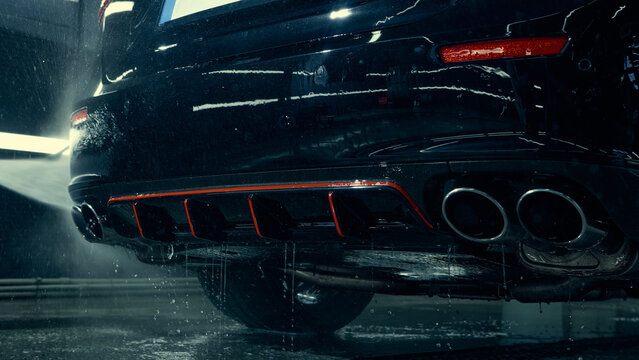 Water rinsing car rear bumper and exhaust after foam cleaning. Concept of auto service maintenance, equipment advertising, and training visuals for car care specialists.
