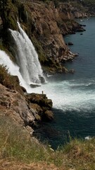 Dramatic high-angle view of the Lower Duden Waterfall in Antalya, Turkey, where massive volumes of water rush down rocky cliffs to meet the deep blue Mediterranean Sea