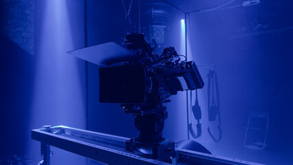 Professional film camera setup in a dark studio with dramatic blue light. Cinematic Sensual tension atmosphere capturing the creative process and visual storytelling of modern film production.
