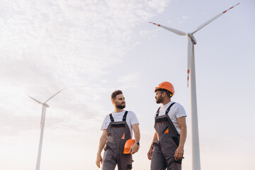 Arabian engineers walking and discussing near wind turbines
