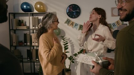 Group of young people congratulating their senior female colleague with retirement, then taking selfie together
