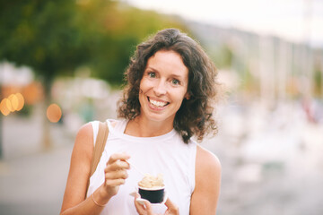 Outdoor portrait of happy candid woman eating ice cream