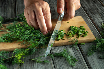 Hands skillfully chop vibrant green herbs on a wooden cutting board, surrounded by fresh ingredients in a cozy kitchen. A culinary scene full of flavor and creativity