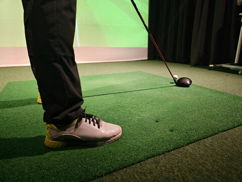 Golf swing practice session taking place indoors with a focus on foot