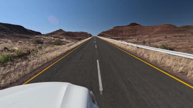 A white car drives on an asphalt road in southern Namibia, Africa.