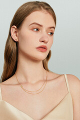 Elegant woman in gold jewelry wearing a satin top, captured in a close-up shot with a modern atmosphere. © Yuanxing
