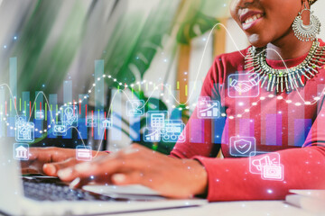 Woman working on laptop with digital graphs and icons in an office setting focused on data analysis and creativity