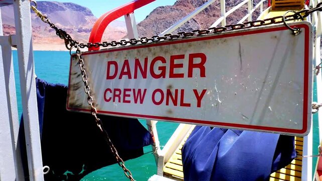 Danger Crew Only sign swinging on a boat with rusty chains