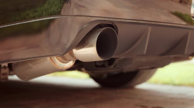 Close view shows muscle car exhaust tip vibrating as engine starts and rumbles