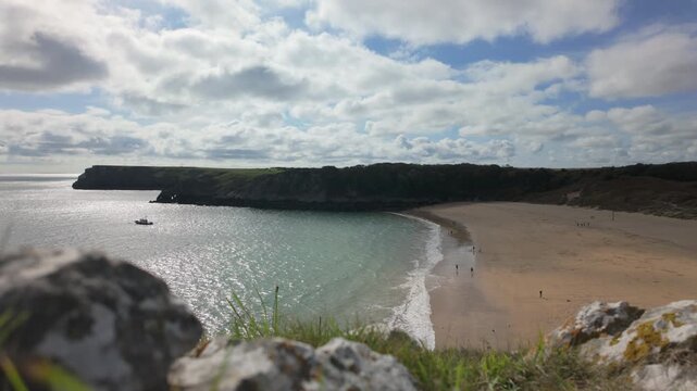 Establishing shot of Barafundle Bay Beach on the Pembrokeshire coast, Wales on a bright summers day with a calm sea.