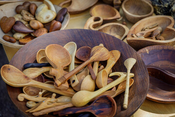 Handcrafted wooden spoons, bowls, and heart-shaped ornaments displayed at a rustic artisan market stall, showcasing natural wood grain and traditional craftsmanship.